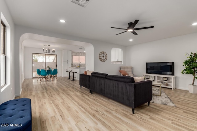 10625 E Bramble Ave, Mesa, AZ 85208 - living room featuring a chandelier, light wood-type flooring, ceiling fan, arched walkways, and recessed lighting