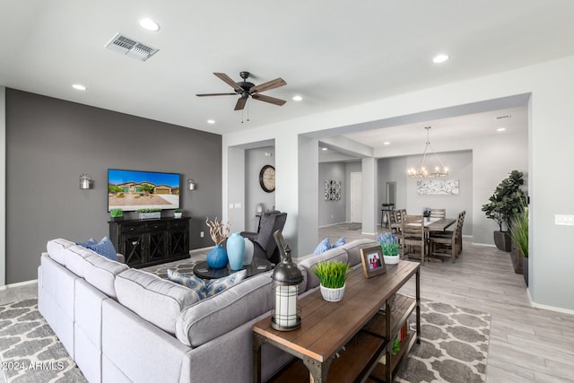 living room with ceiling fan with notable chandelier and light hardwood / wood-style flooring