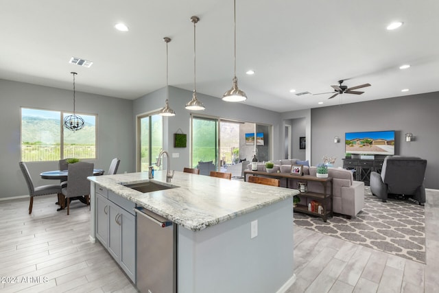 kitchen featuring pendant lighting, sink, a center island with sink, and light wood-type flooring