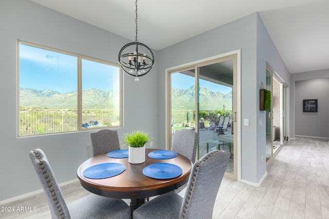 dining area with light hardwood / wood-style floors, a mountain view, an inviting chandelier, and vaulted ceiling