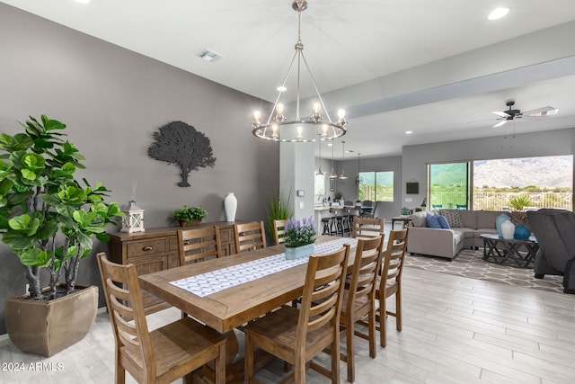 dining space featuring light wood-type flooring and ceiling fan with notable chandelier