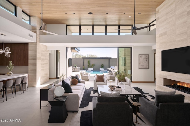 living room featuring ceiling fan, wood ceiling, a tile fireplace, and a high ceiling