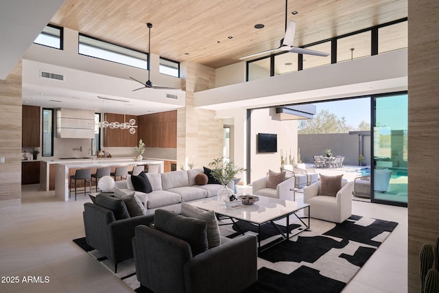 living room with a high ceiling, ceiling fan, light tile patterned floors, and wood ceiling