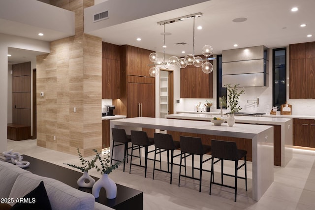 kitchen featuring a large island, pendant lighting, a breakfast bar, and wall chimney range hood