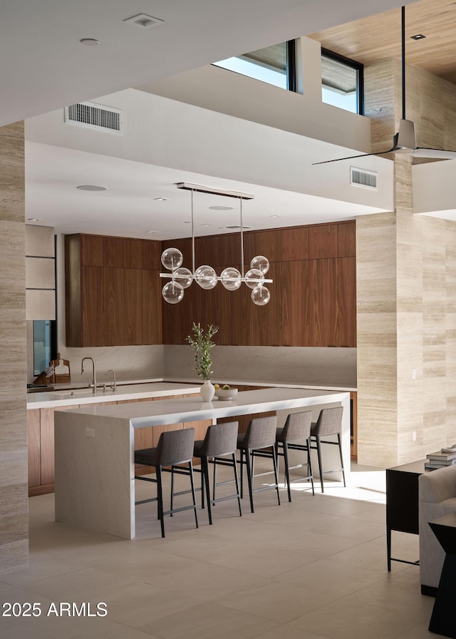 kitchen with wood walls, a center island, light tile patterned floors, a kitchen bar, and decorative light fixtures