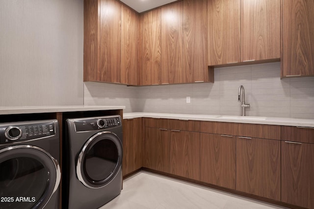 laundry area with sink, washing machine and dryer, and cabinets