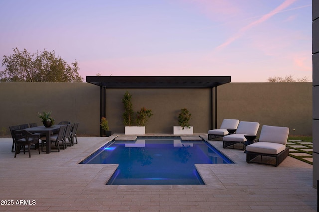 pool at dusk with a patio area