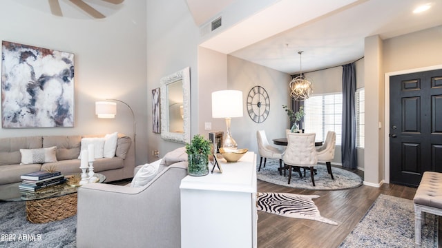 living room with ceiling fan with notable chandelier and dark hardwood / wood-style flooring