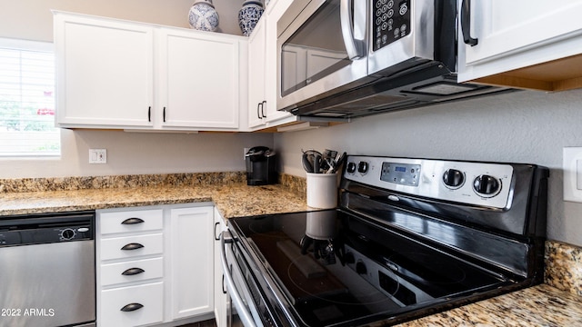 kitchen featuring light stone counters, white cabinetry, and stainless steel appliances