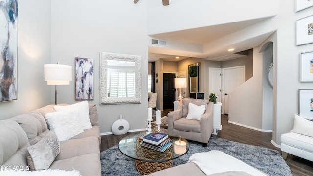 living room featuring a high ceiling, ceiling fan, and dark wood-type flooring