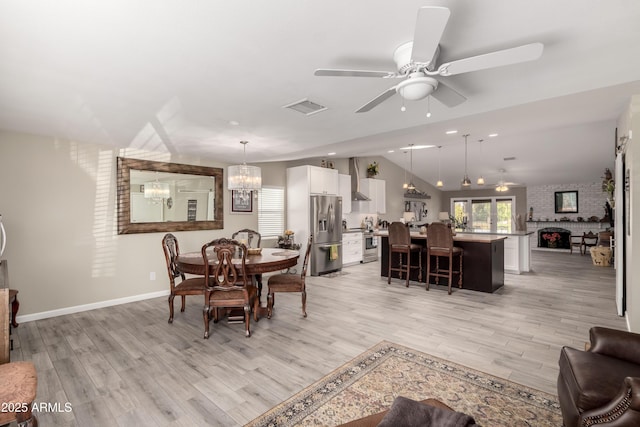 dining room featuring lofted ceiling, light wood-style flooring, visible vents, and ceiling fan with notable chandelier