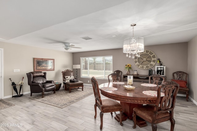 dining space featuring light wood-style floors, visible vents, baseboards, and ceiling fan with notable chandelier