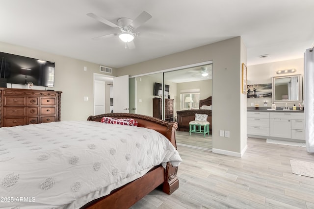 bedroom with ceiling fan, light wood-style flooring, visible vents, a closet, and ensuite bath