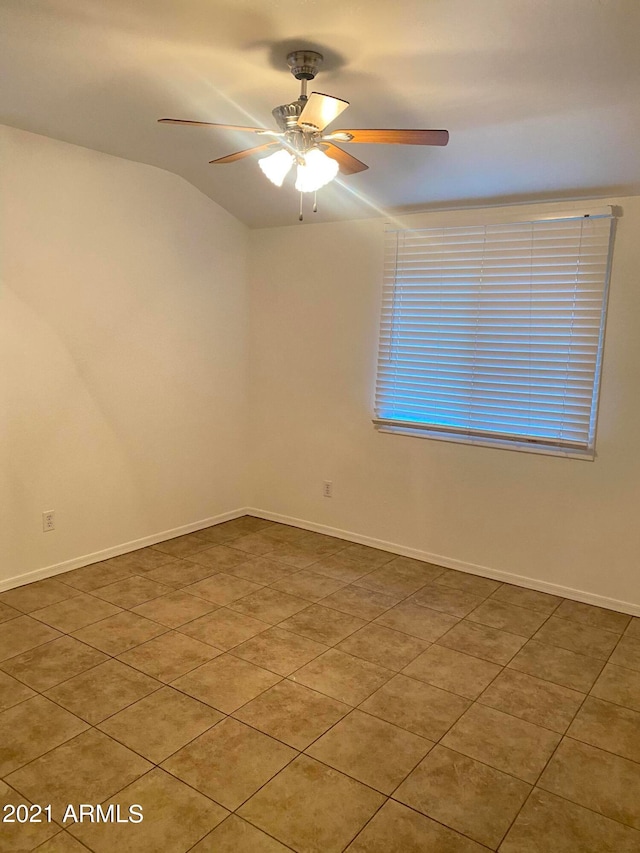 tiled empty room featuring ceiling fan and vaulted ceiling