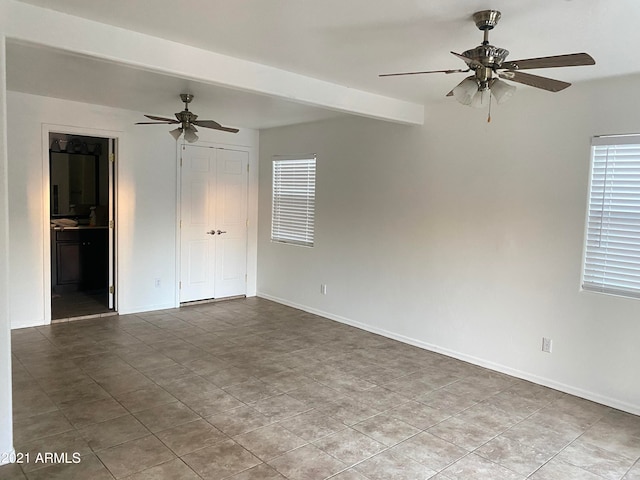 spare room with a wealth of natural light, ceiling fan, beam ceiling, and light tile patterned floors