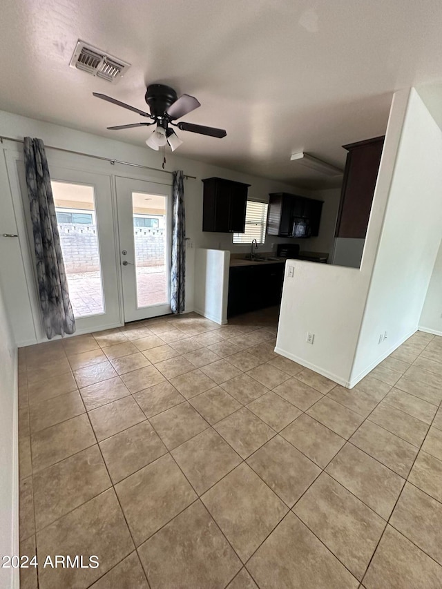 unfurnished living room featuring sink, french doors, ceiling fan, and light tile patterned floors