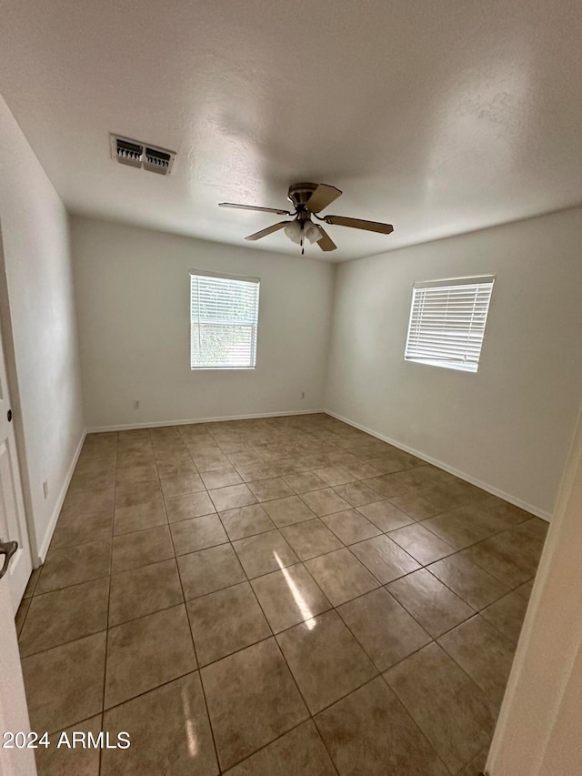 tiled spare room with ceiling fan