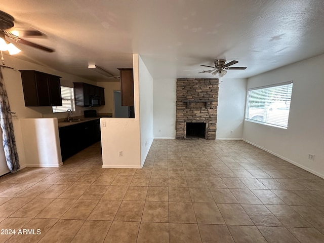 unfurnished living room with sink, light tile patterned floors, a fireplace, and ceiling fan