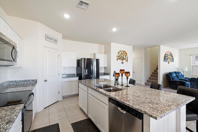 kitchen featuring sink, a breakfast bar, appliances with stainless steel finishes, white cabinetry, and an island with sink