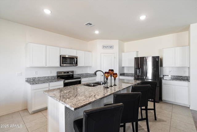 kitchen with sink, white cabinets, a kitchen island with sink, light stone counters, and stainless steel appliances