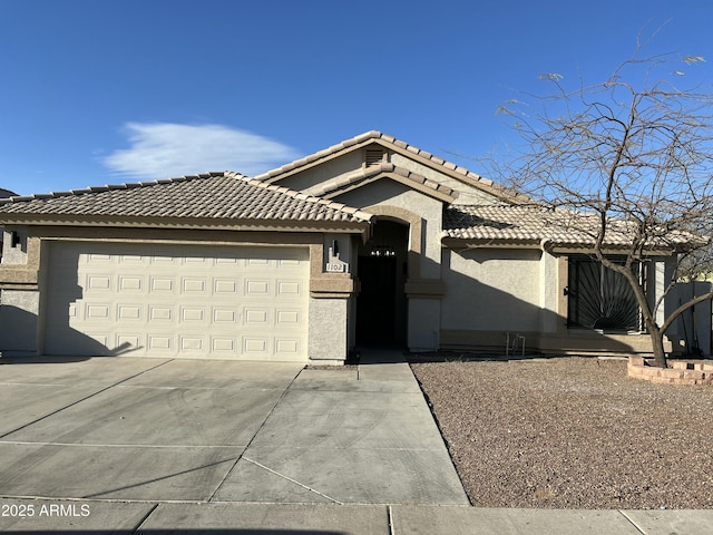 view of front of home featuring a tile roof, stucco siding, concrete driveway, and a garage