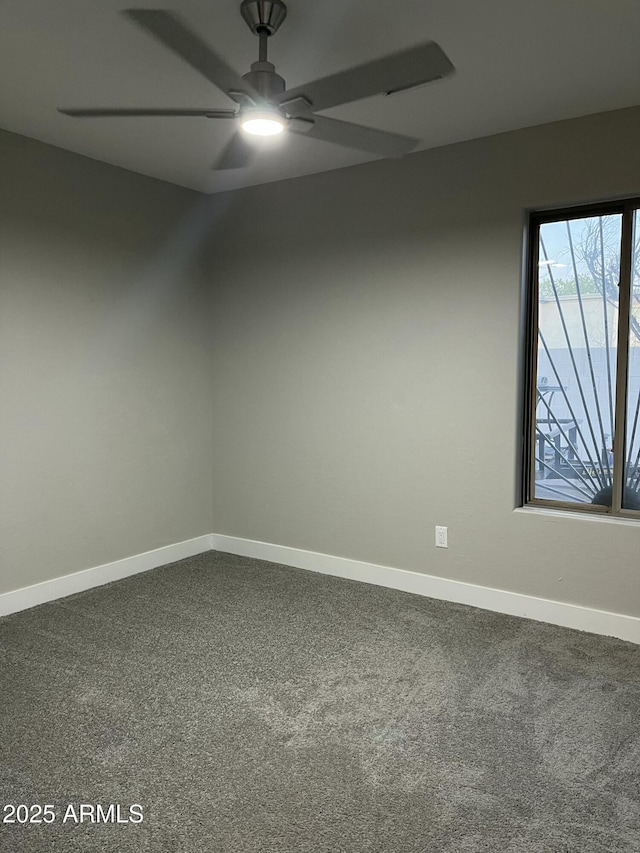 unfurnished room with baseboards, ceiling fan, and dark carpet