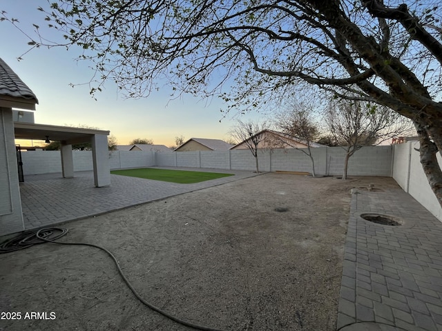 yard at dusk featuring a patio and a fenced backyard