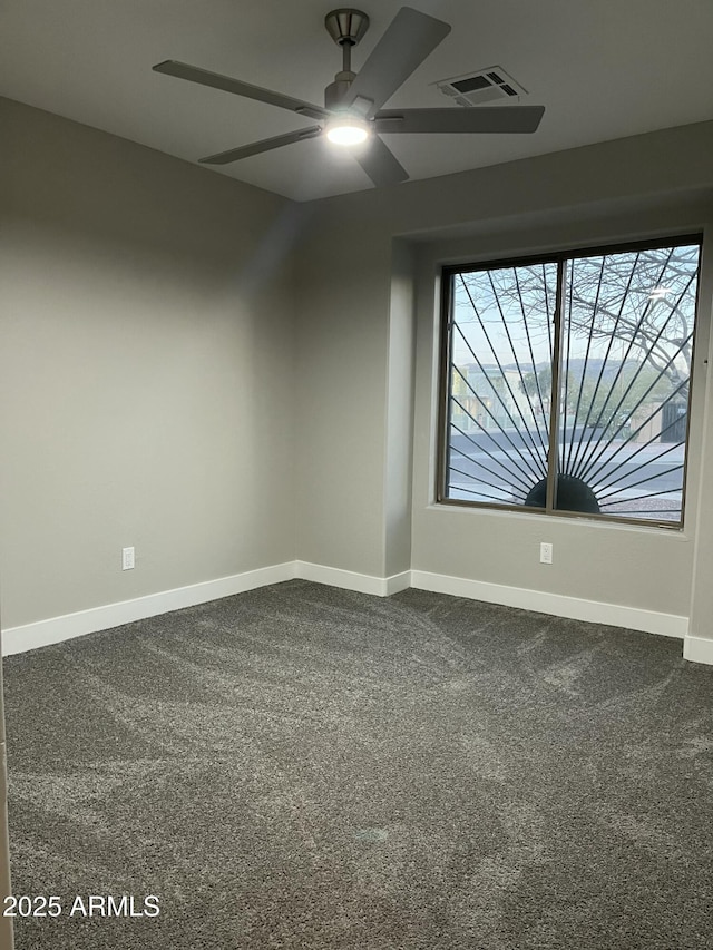 unfurnished room with visible vents, dark carpet, baseboards, and ceiling fan