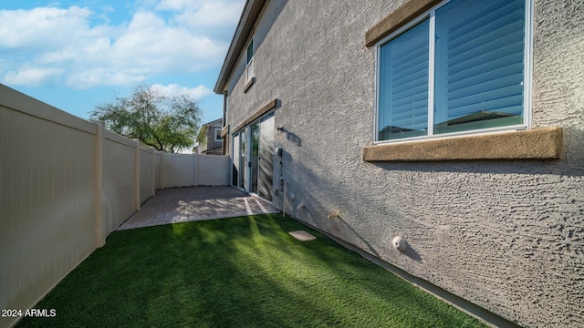 view of side of home with a patio and a lawn