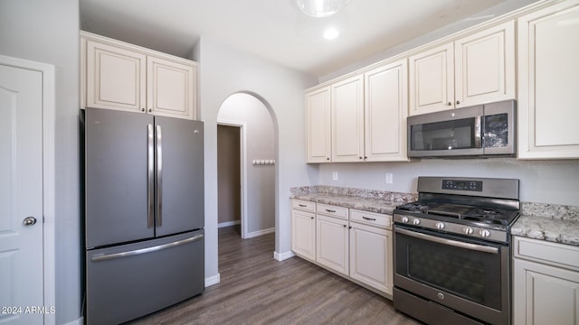 kitchen featuring white cabinets, appliances with stainless steel finishes, light stone countertops, and wood-type flooring