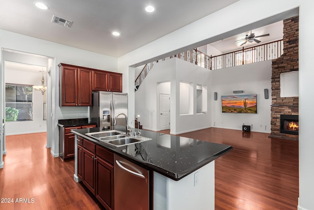 kitchen featuring dark wood-type flooring, appliances with stainless steel finishes, sink, and a center island with sink