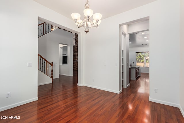 unfurnished dining area with a notable chandelier, sink, and dark wood-type flooring