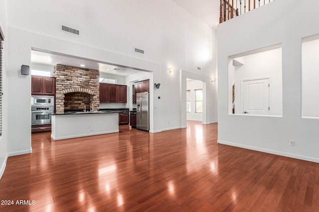 unfurnished living room featuring sink, dark hardwood / wood-style floors, and a towering ceiling