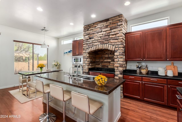 kitchen featuring dark hardwood / wood-style floors, stainless steel appliances, a center island with sink, and a kitchen bar