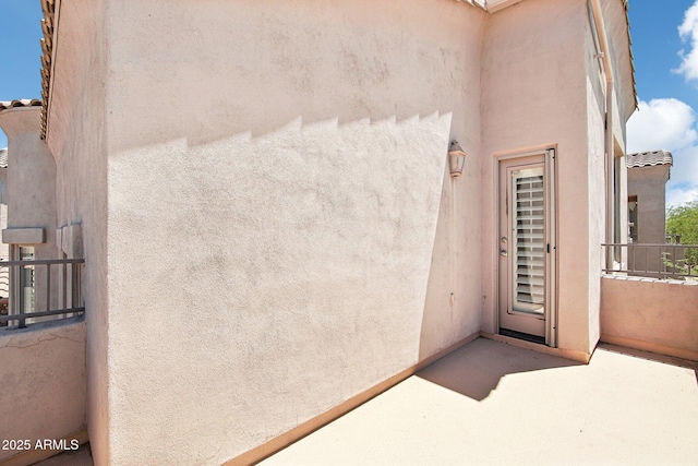 entrance to property with stucco siding and a balcony