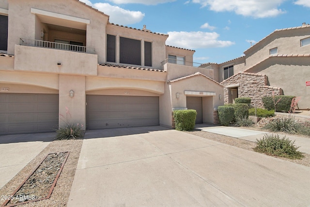 view of front of house with stucco siding, a balcony, concrete driveway, and a tile roof