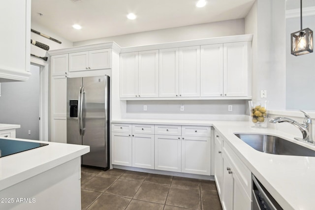 kitchen featuring appliances with stainless steel finishes, a sink, white cabinets, dark tile patterned flooring, and light countertops
