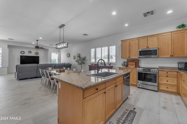 kitchen featuring appliances with stainless steel finishes, light wood-type flooring, ceiling fan, a center island with sink, and sink