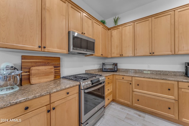 kitchen featuring light brown cabinets, light stone countertops, and stainless steel appliances