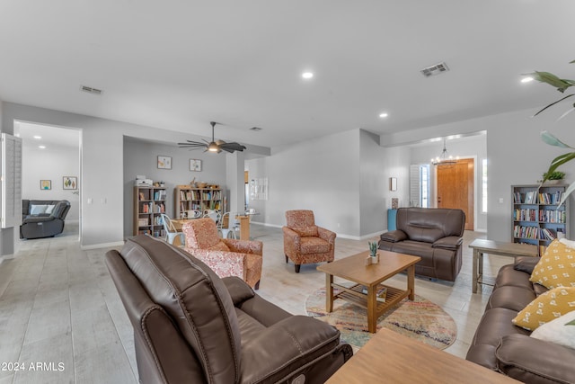 living room with ceiling fan with notable chandelier and light hardwood / wood-style flooring