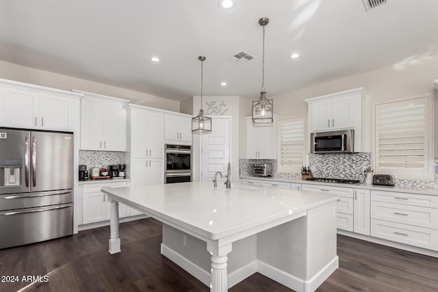 kitchen with a kitchen island with sink, appliances with stainless steel finishes, decorative light fixtures, dark hardwood / wood-style flooring, and white cabinetry