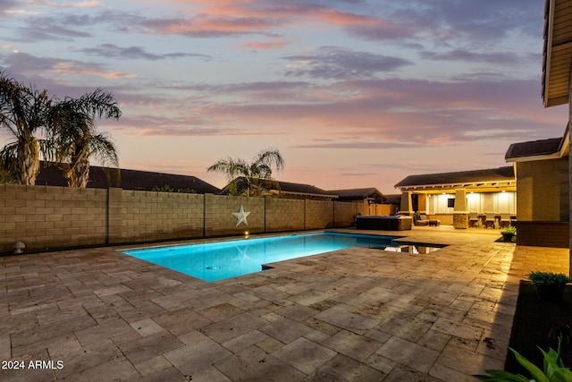 pool at dusk featuring a jacuzzi and a patio