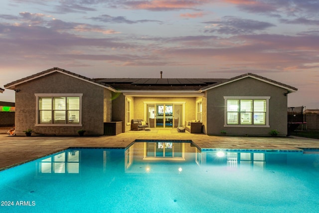 pool at dusk featuring a patio area