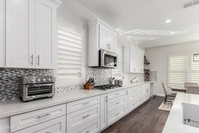 kitchen featuring backsplash, dark hardwood / wood-style flooring, white cabinets, and appliances with stainless steel finishes