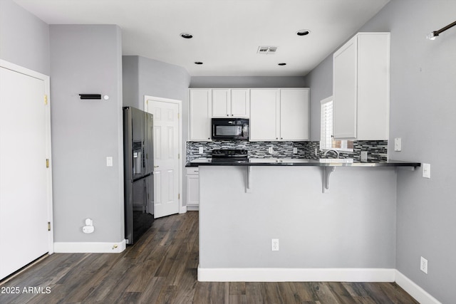 3025 E Fremont Rd, Phoenix, AZ 85042 - kitchen with black appliances, a breakfast bar area, a peninsula, white cabinetry, and backsplash