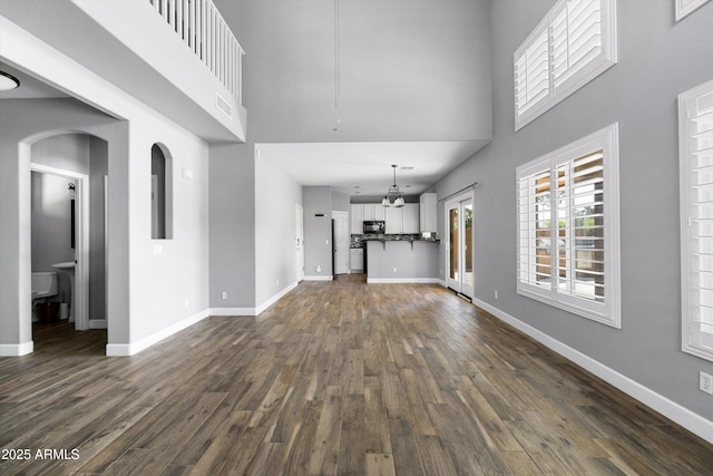 3025 E Fremont Rd, Phoenix, AZ 85042 - unfurnished living room with dark wood-style floors, a high ceiling, a chandelier, and arched walkways