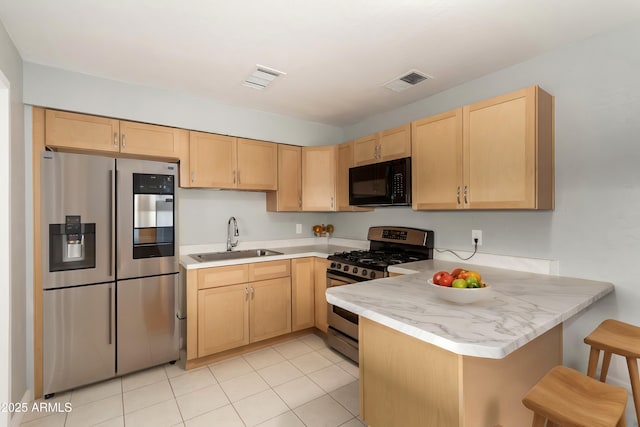 kitchen featuring kitchen peninsula, light brown cabinets, stainless steel appliances, and sink