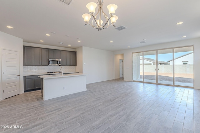 kitchen with gray cabinets, a notable chandelier, sink, decorative light fixtures, and tasteful backsplash