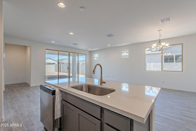 kitchen featuring a chandelier, light stone countertops, pendant lighting, sink, and stainless steel dishwasher