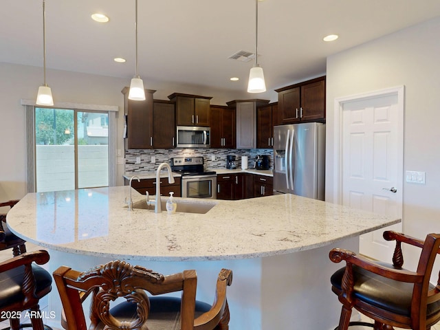 17547 W Gambit Trl, Surprise, AZ 85387 - kitchen featuring appliances with stainless steel finishes, dark brown cabinetry, a kitchen breakfast bar, tasteful backsplash, and a sink